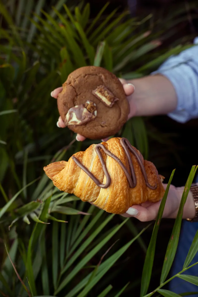 Representative chocolate-drizzled croissant held beside a cookie